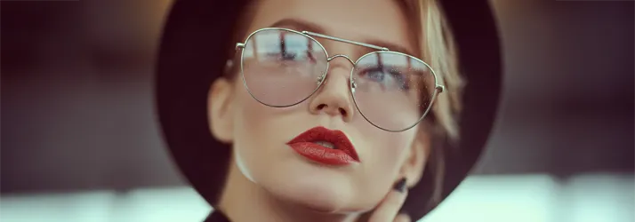 A stylish young woman wearing reflective glasses posing for the camera.