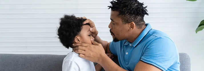 A father looking at his child's eye after an accident, inspecting for damage.
